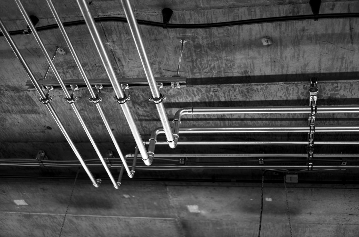 a monochrome photograph featuring pipes hanging from the ceiling