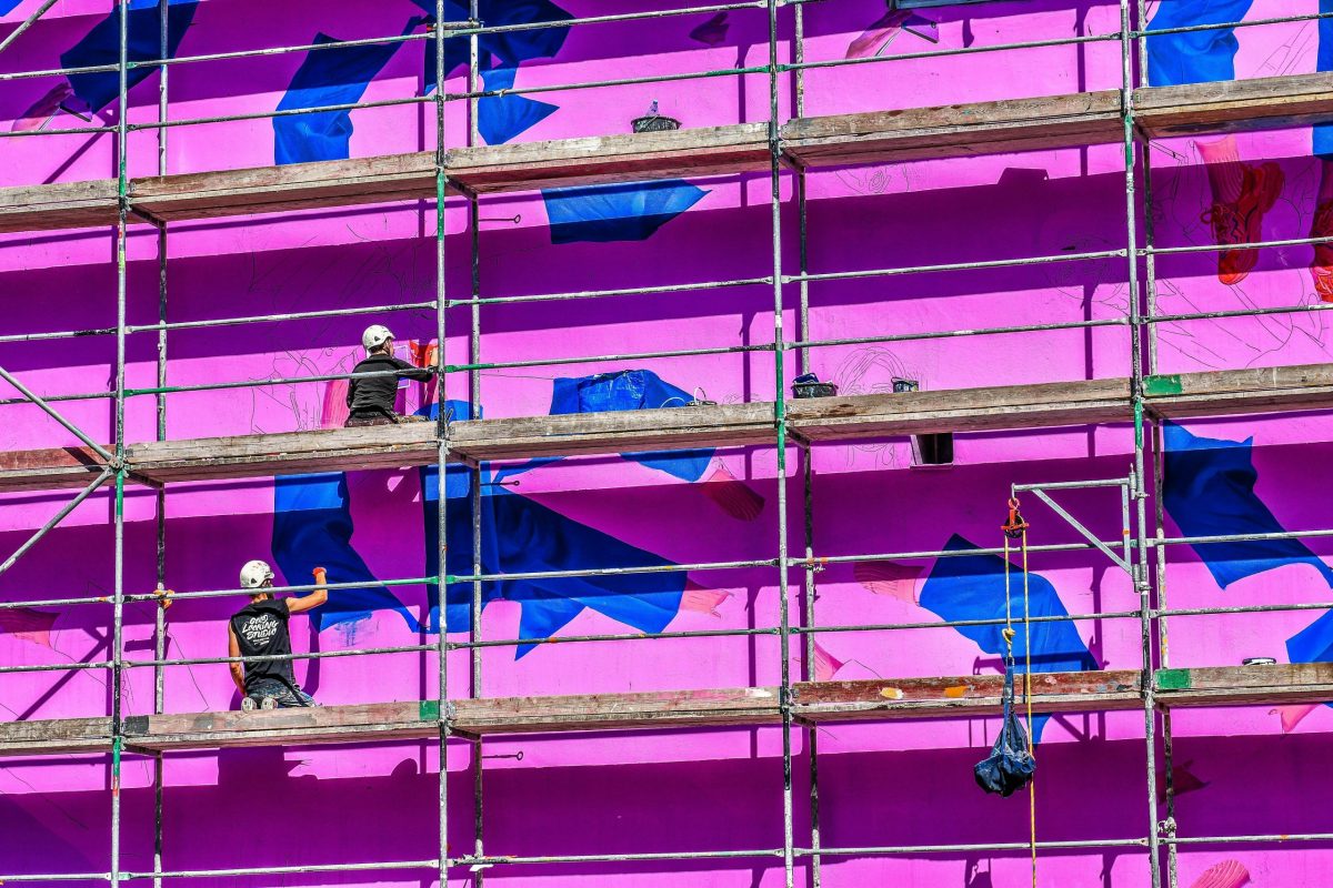 workers on scaffolding painting a building