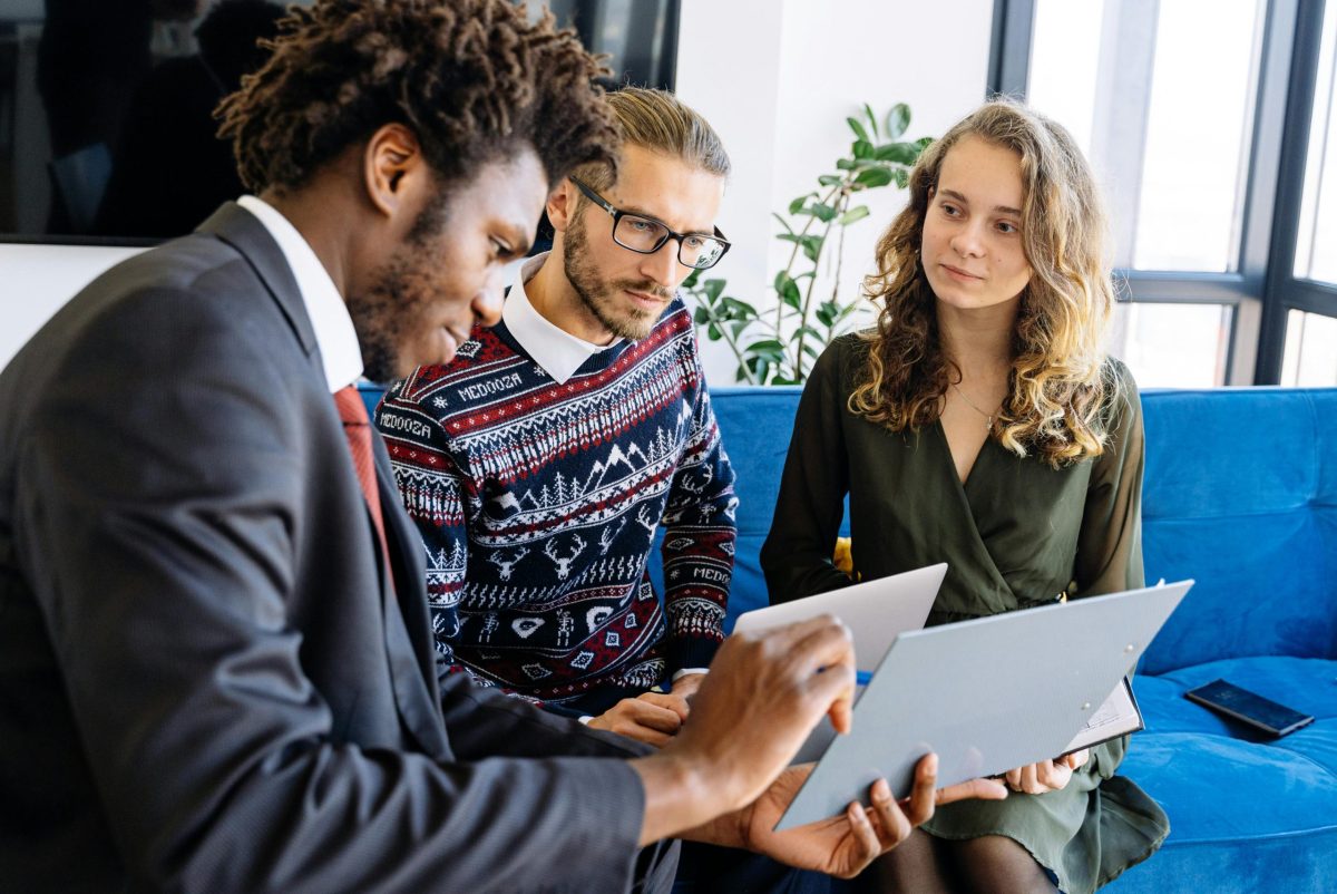 three individuals on a couch reviewing insurance information