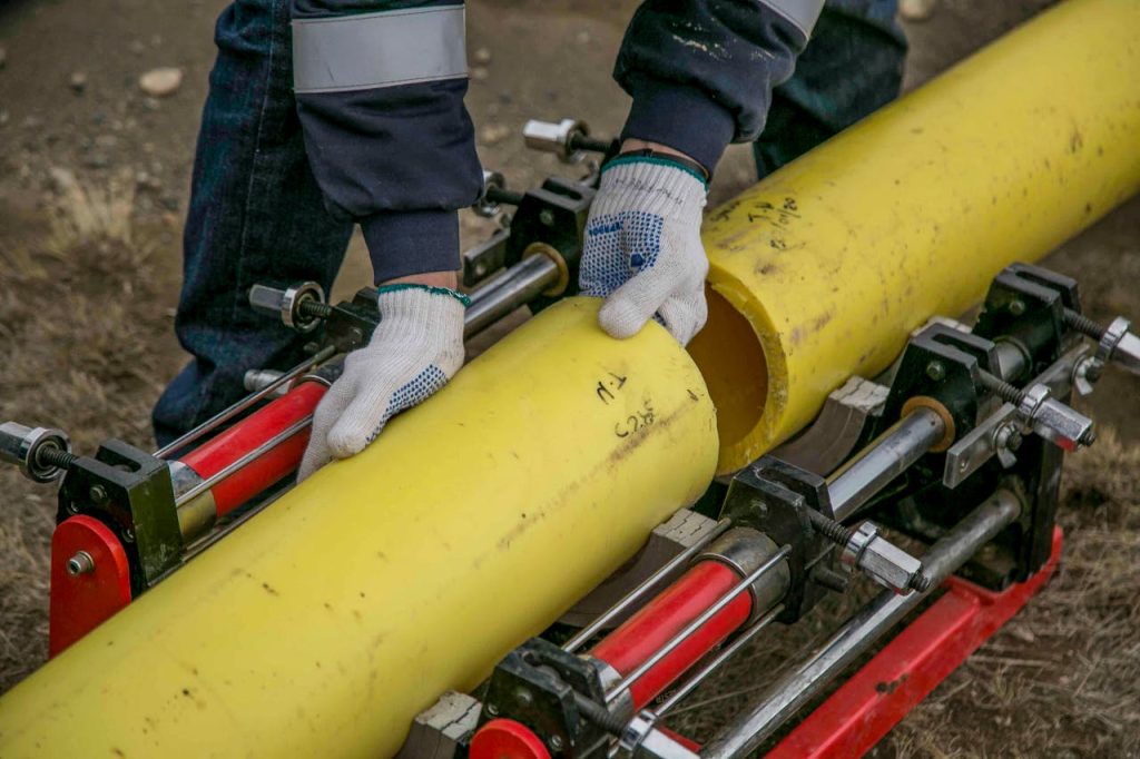 a man wearing a blue shirt and white gloves is gripping a yellow pipe