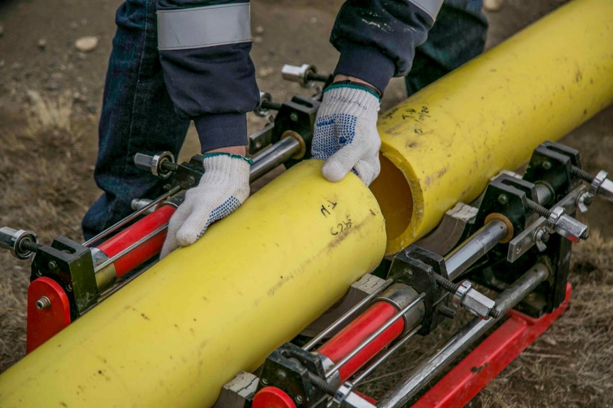 a man wearing a blue shirt and white gloves is gripping a yellow pipe