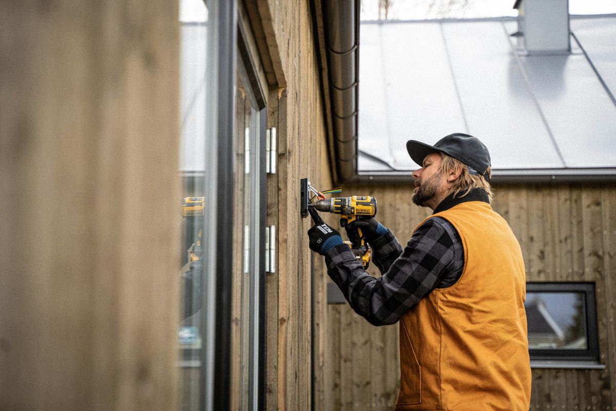 a tradesman wearing an orange vest and black cap examining tools