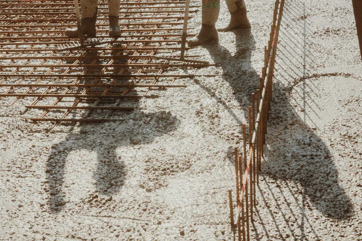 shadows of a construction worker against wire mesh and concrete