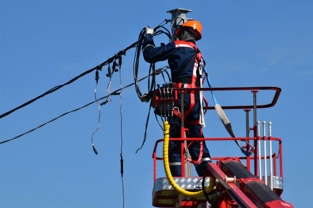 a worker on a ladder engaged in power line maintenance