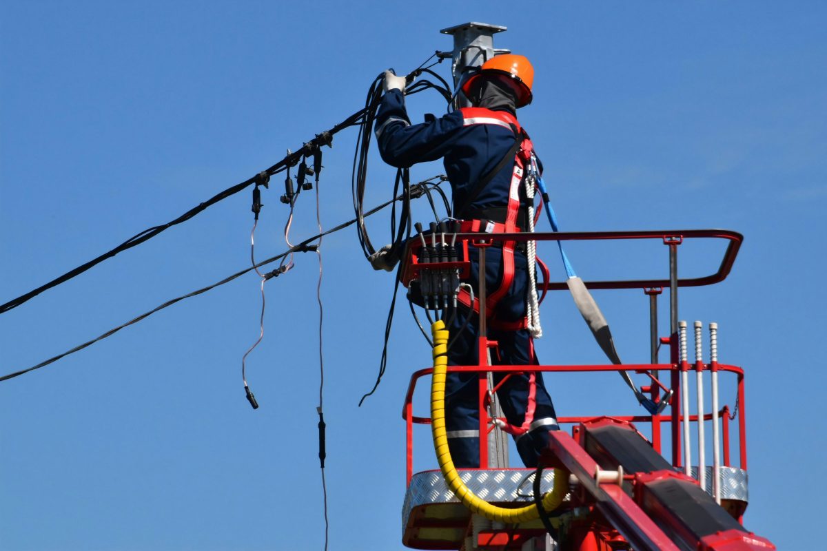 a worker on a ladder engaged in power line maintenance