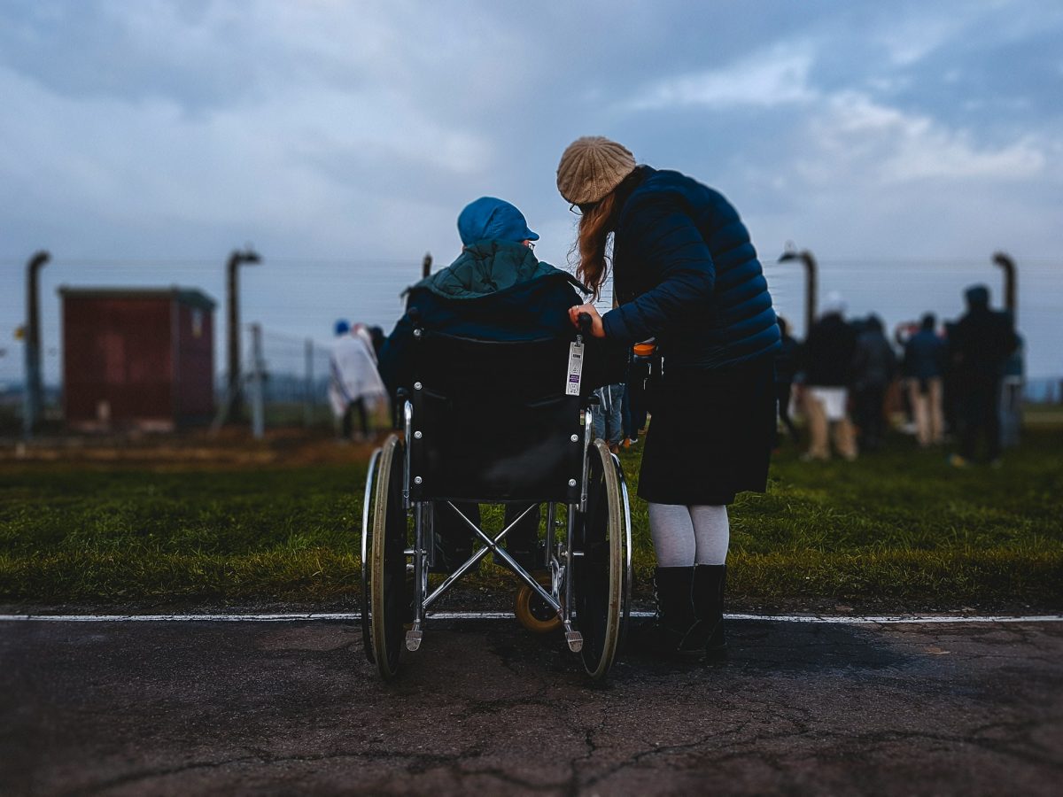 a man in a wheelchair is accompanied by a woman standing beside him