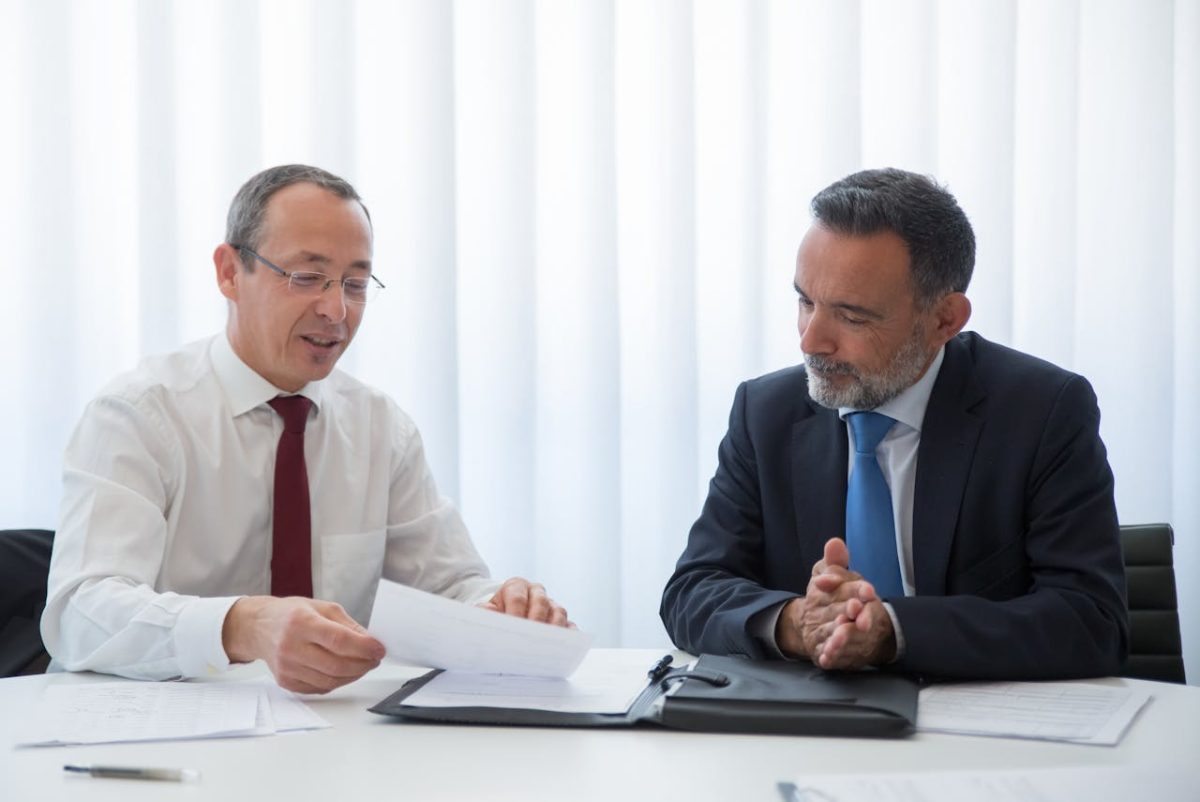 two insurance brokers in business attire engaged in conversation at a table