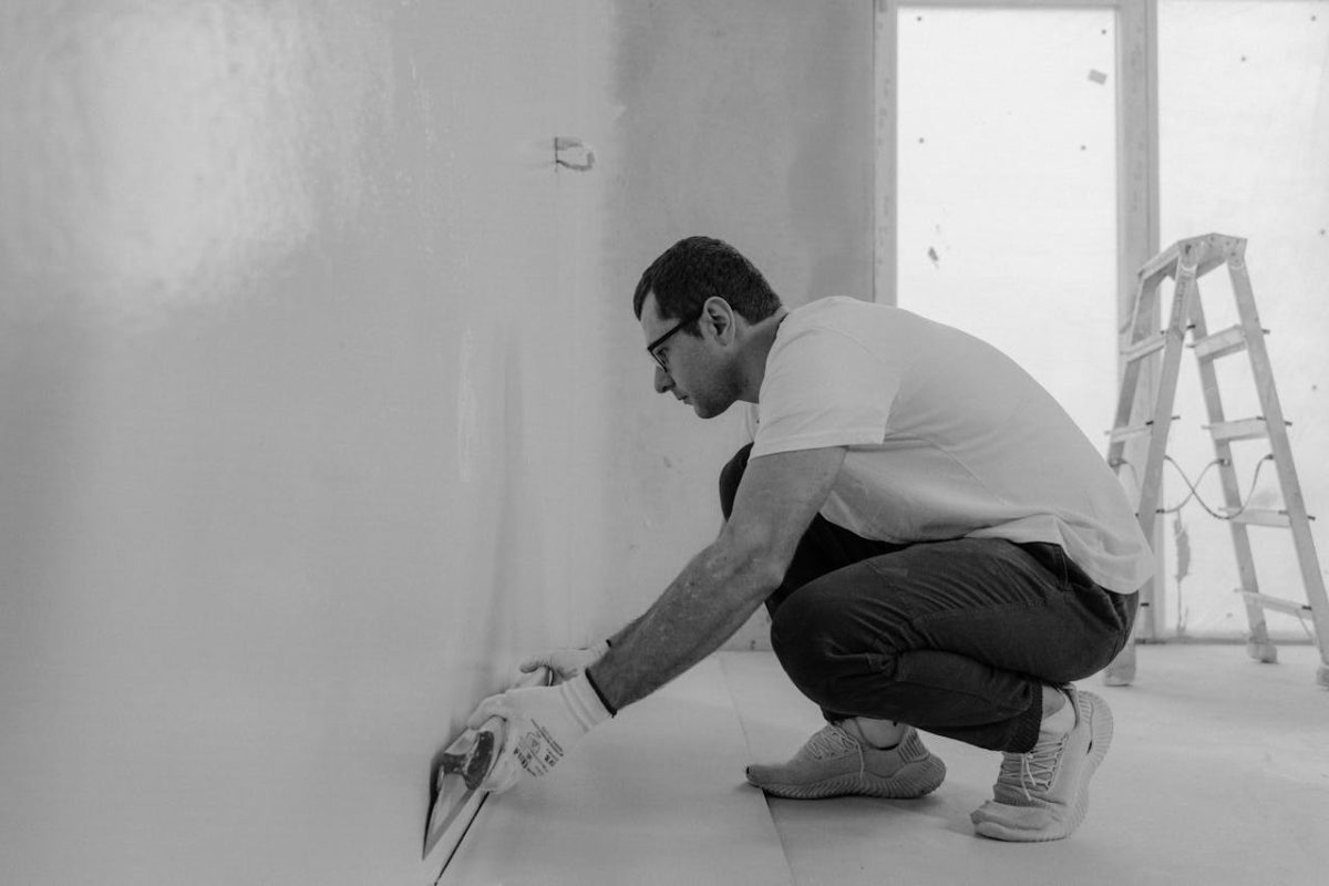 a craftsman applying plaster to a wall in a bright, minimalist workspace