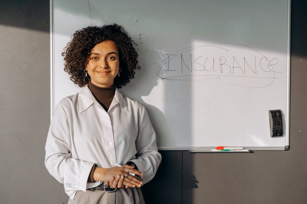 a woman stands before a whiteboard that features the word insurance
