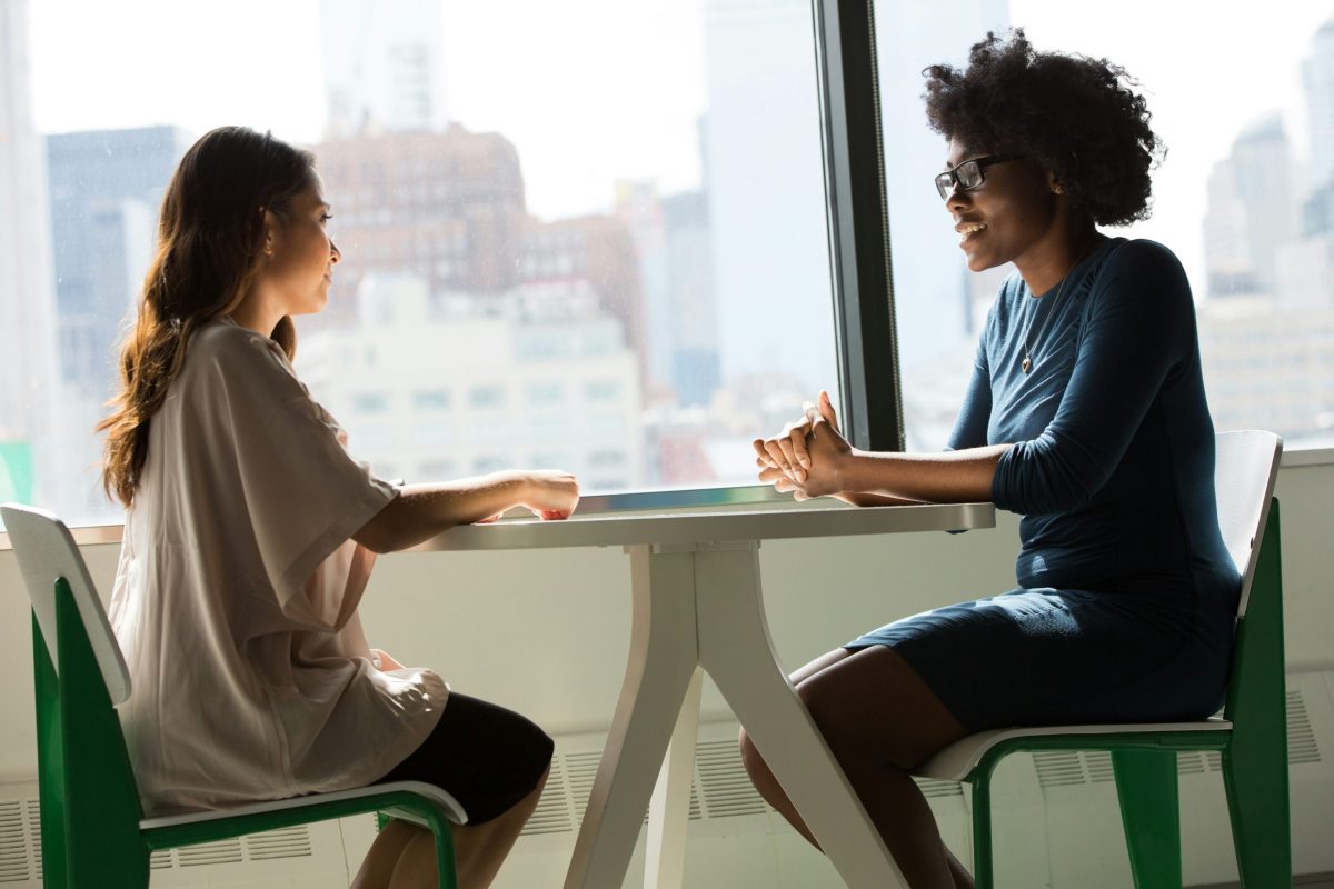 two women engaged in conversation while seated at a table