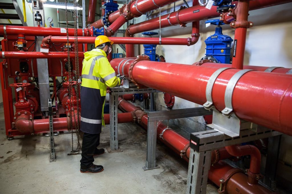 a man wearing a safety vest stands next to a large pipe
