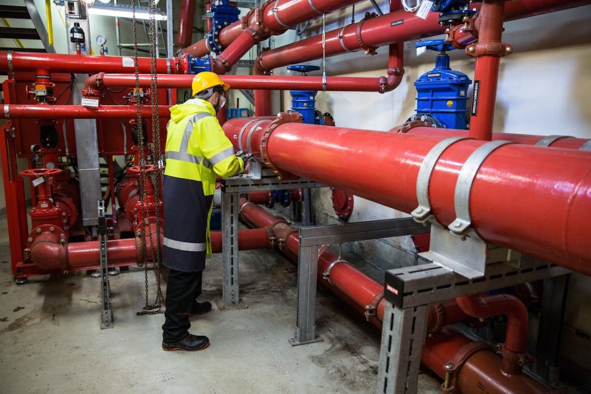 a man wearing a safety vest stands next to a large pipe