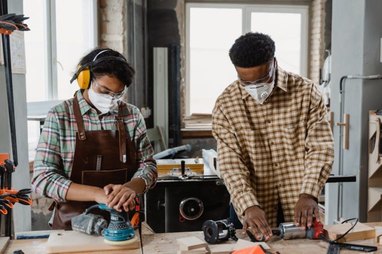 Two people collaborating on woodworking projects surrounded by tools
