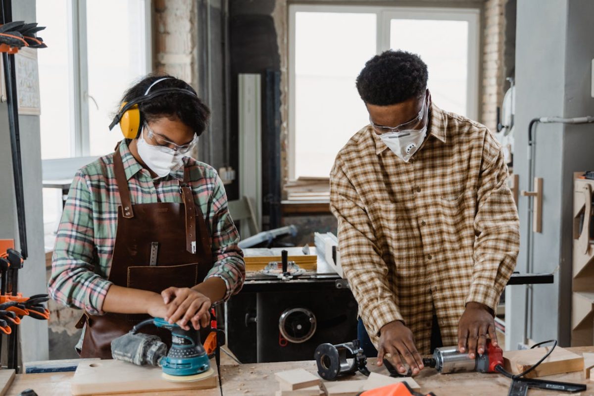 Two people collaborating on woodworking projects surrounded by tools