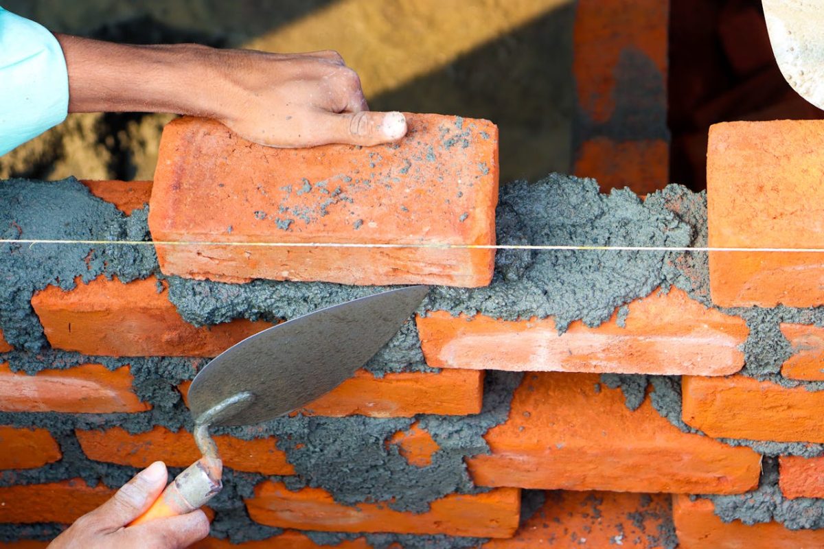 an individual is engaged in building a brick wall