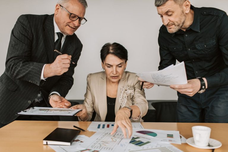 a trio of business individuals examining papers and documents together