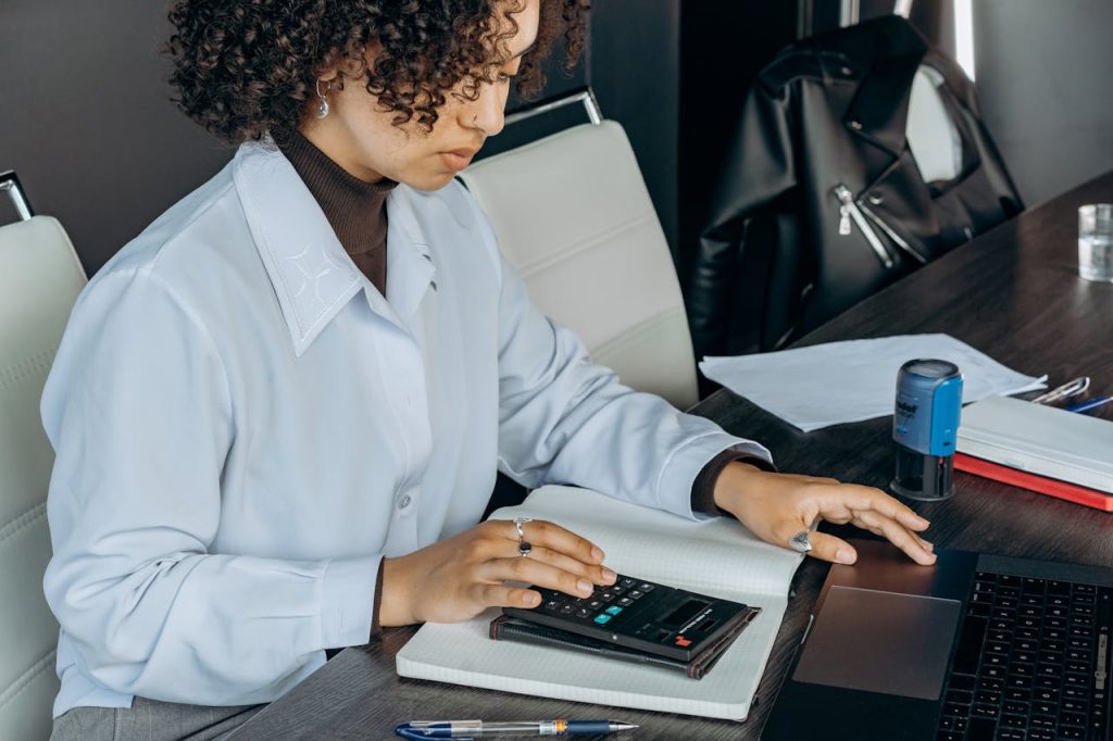 a woman in a white shirt is focused on using a calculator for calculations