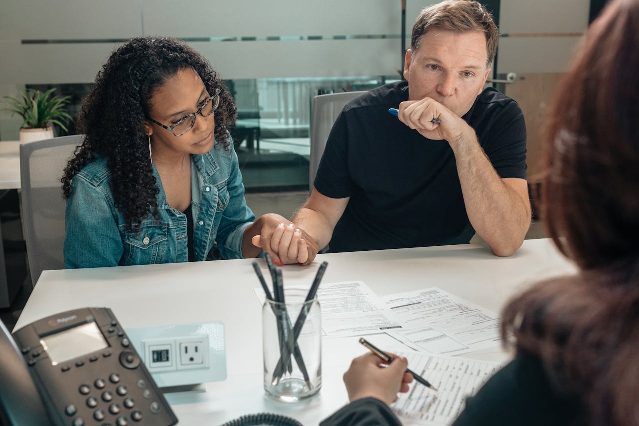 A man and woman at a table, engaged in discussion while examining documents.