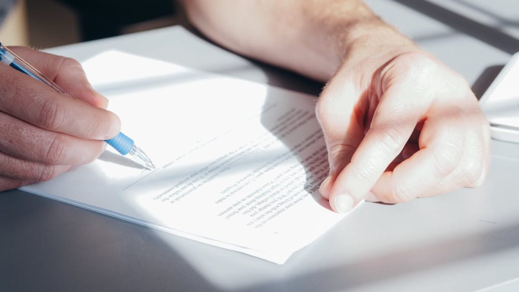 a man signing a contract with a pen, related to cyber insurance claims