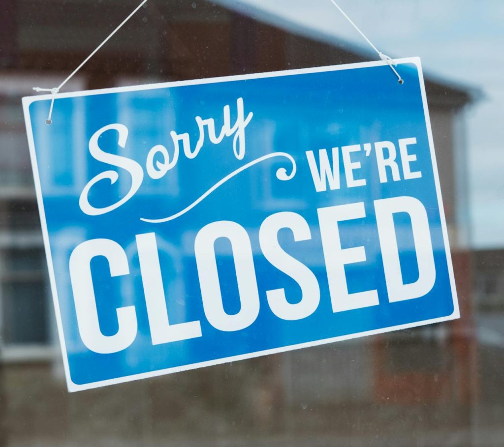 a closed sign hanging in a window, indicating business interruption to customers