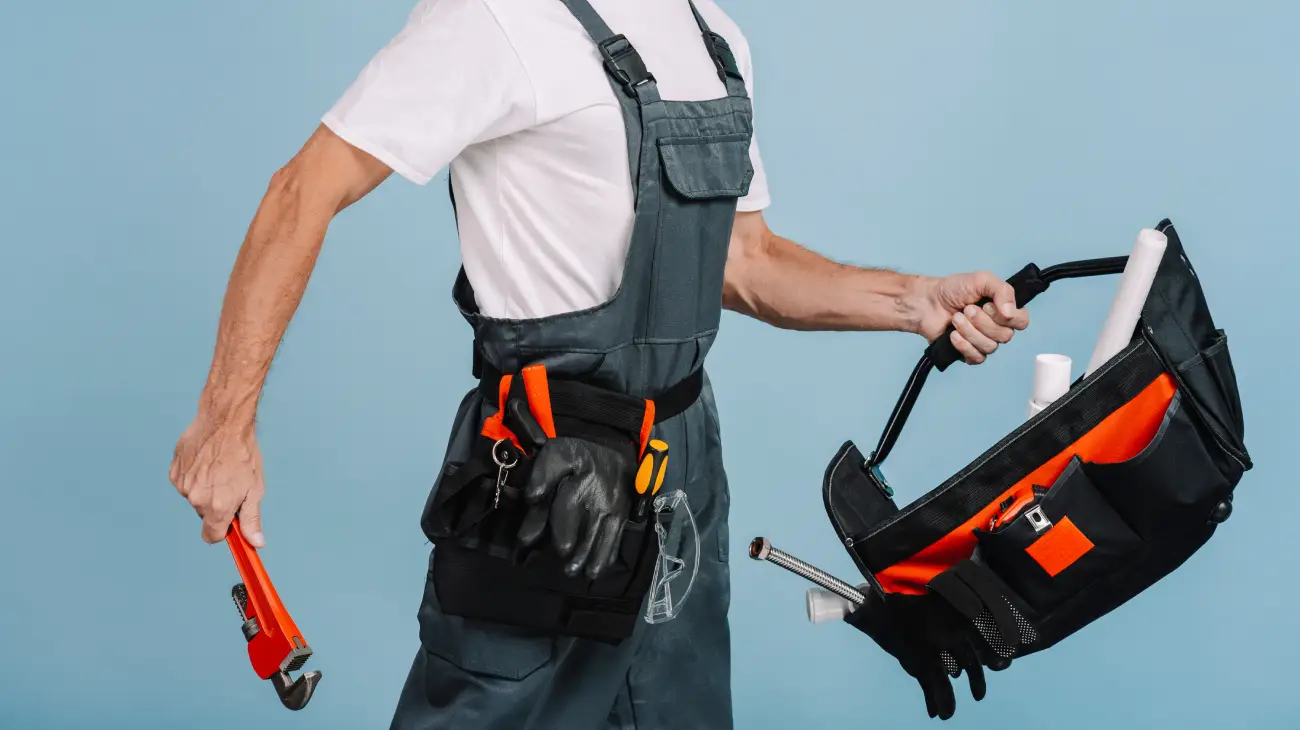 Plumber holding pipe wrench and tool bag