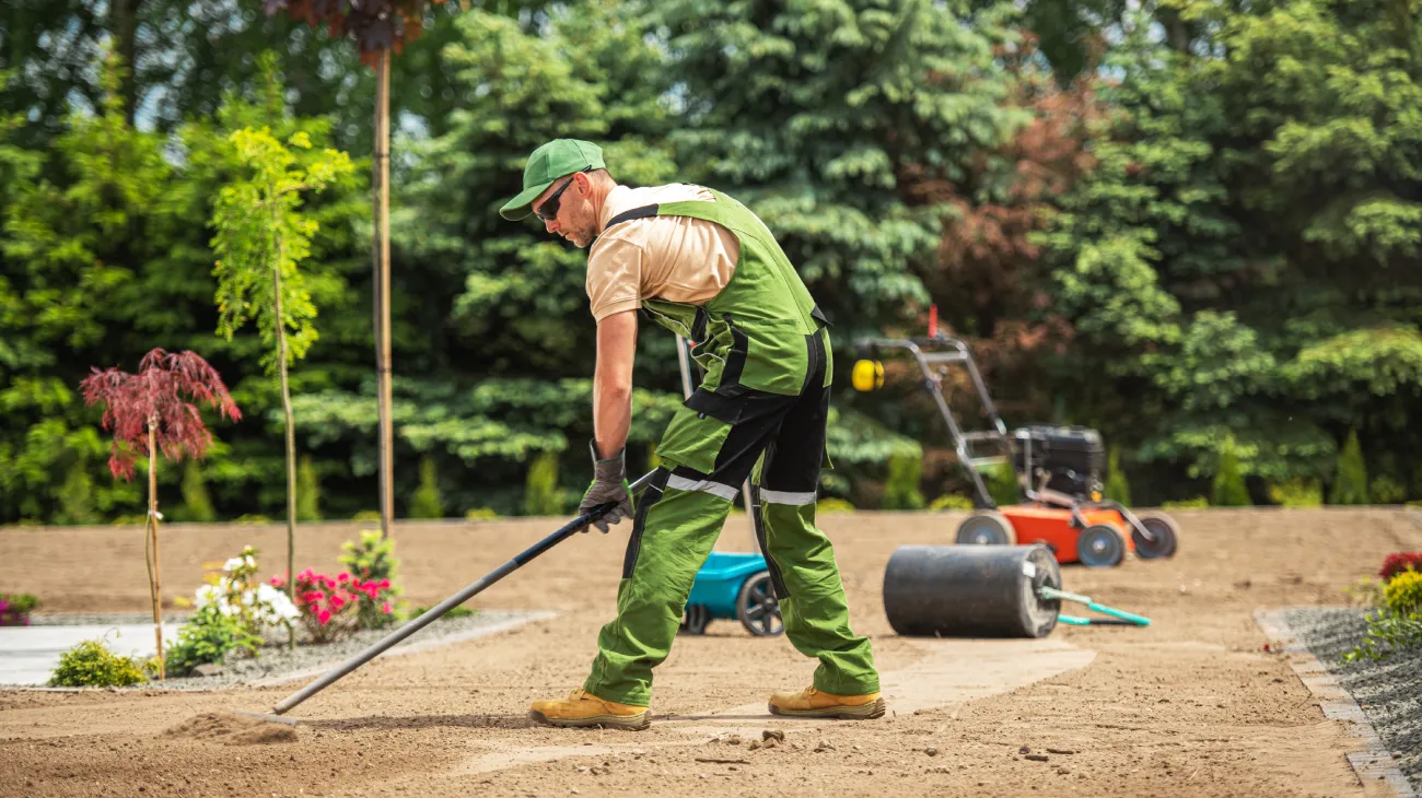 Landscaper spreading soil in a green garden